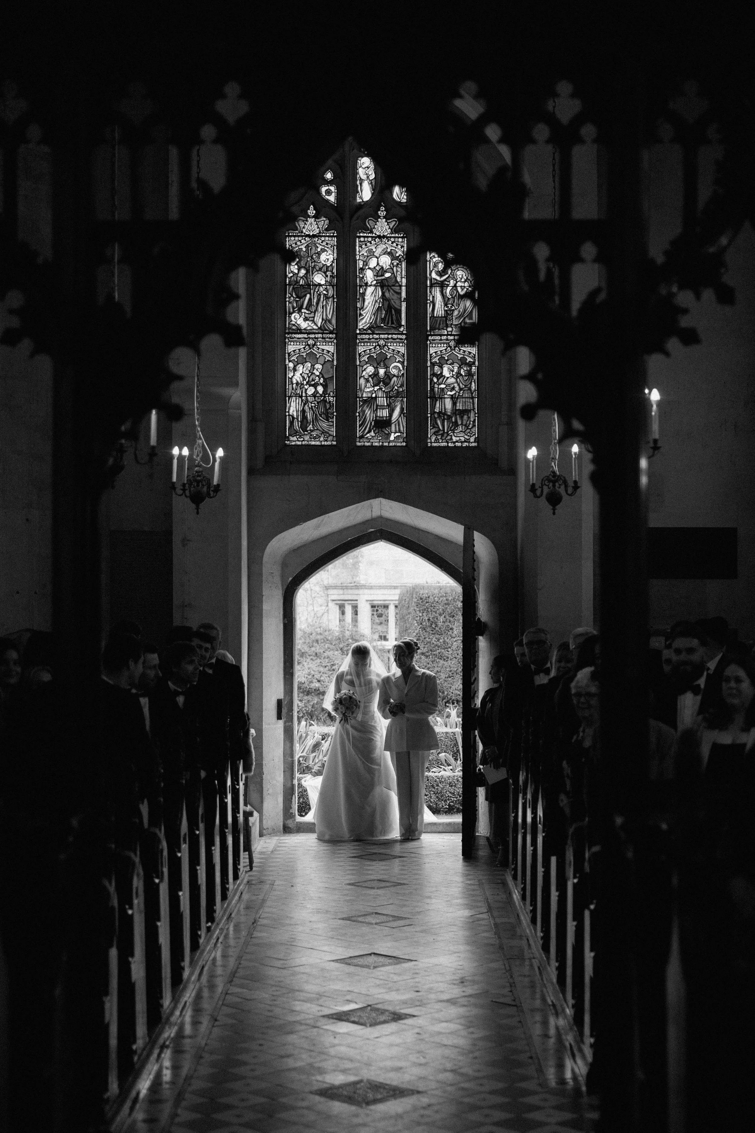 Dramatic Black and white photo of Bride entering the chapel at Sudeley Castle arm in arm with the mother of the bride