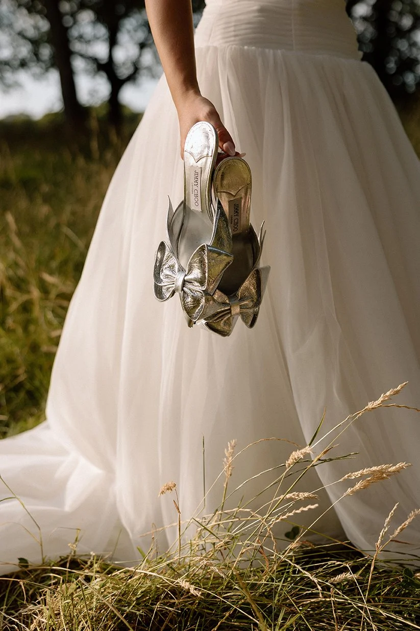bride holding jimmy choos in golden hour