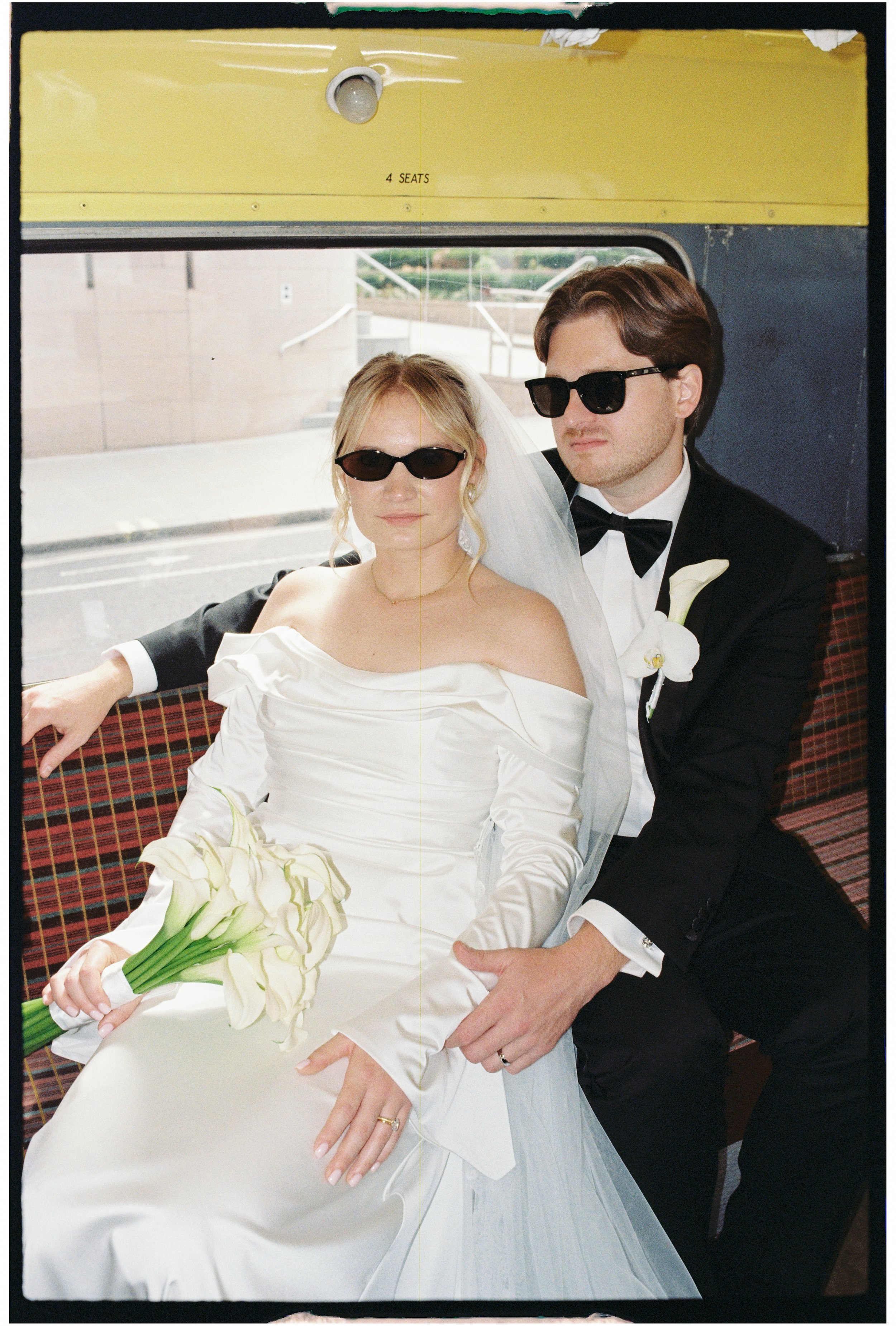 35mm photo of bride and groom looking stylish on their route-master bus after their London wedding