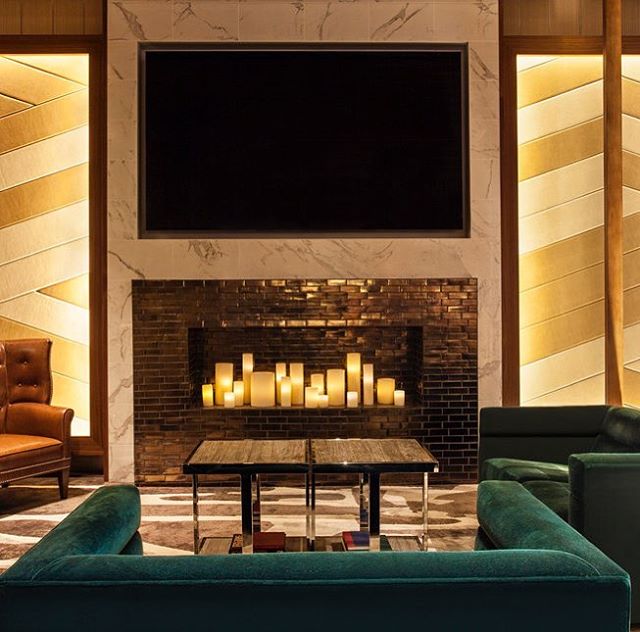 The up-lit wood screens create a sense of drama, while a candlelit fireplace adds the warmth and comfort of the residential hearth to the Westin Hotel Time Square lobby. The neutral color palette, with luxurious fabrics and pops of green, adds an und