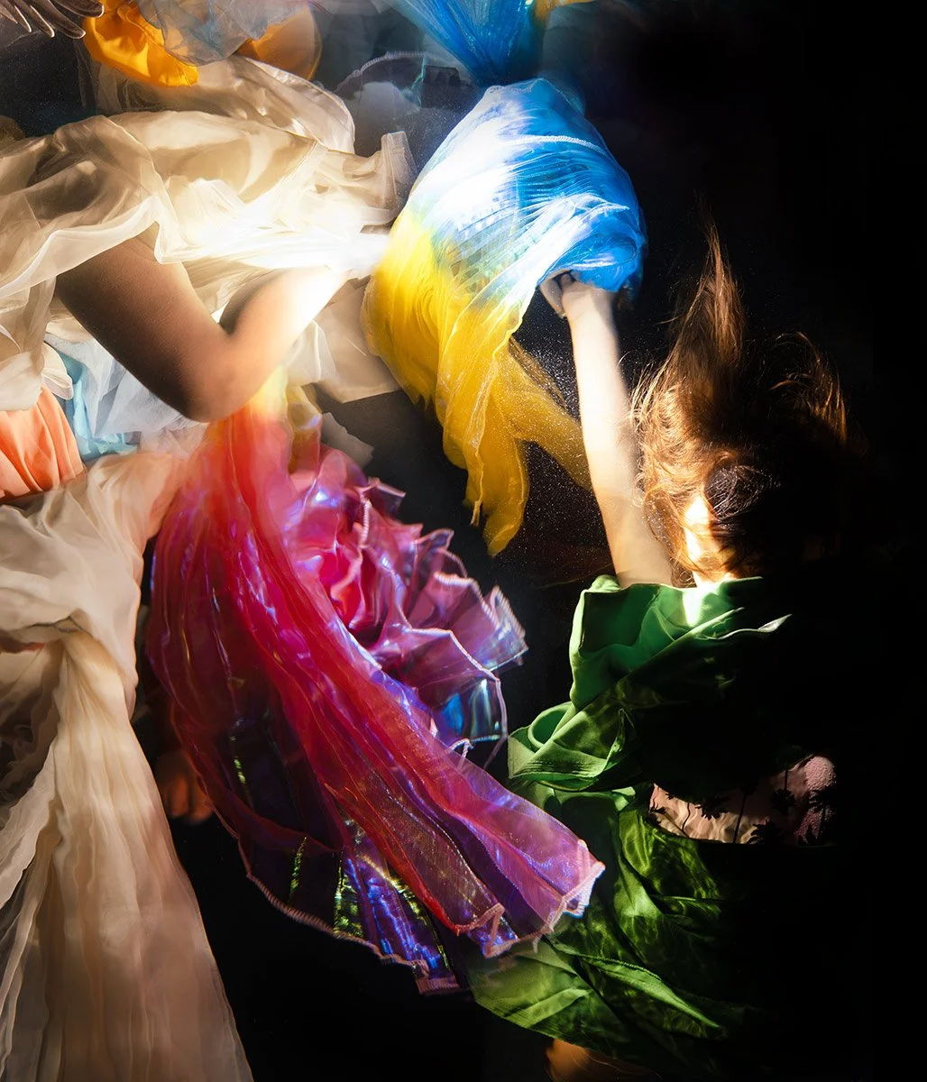 “Myth and Mercy”by Christy Lee Rogers is an underwater photograph from her Myths and Legends collection, depicting multiple figures suspended in an inky abyss.