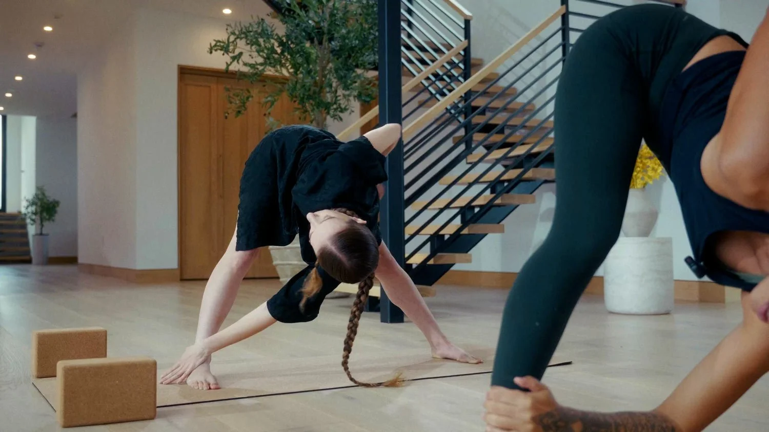 two yoginis in revolved triangle pose in a yoga class