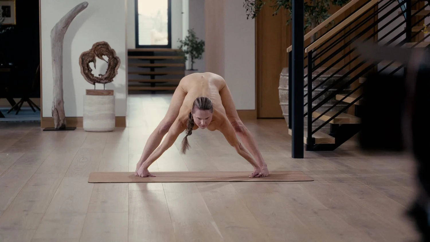 nude woman in wide legged forward fold