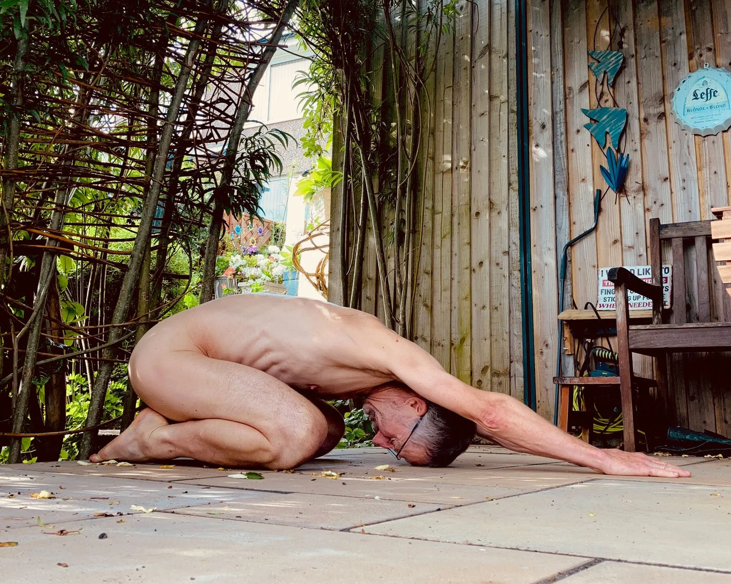 Naked man in childs pose outside