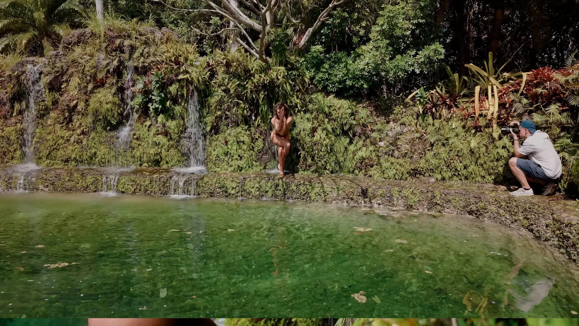 nude woman in eagle pose in tropical location with waterfalls