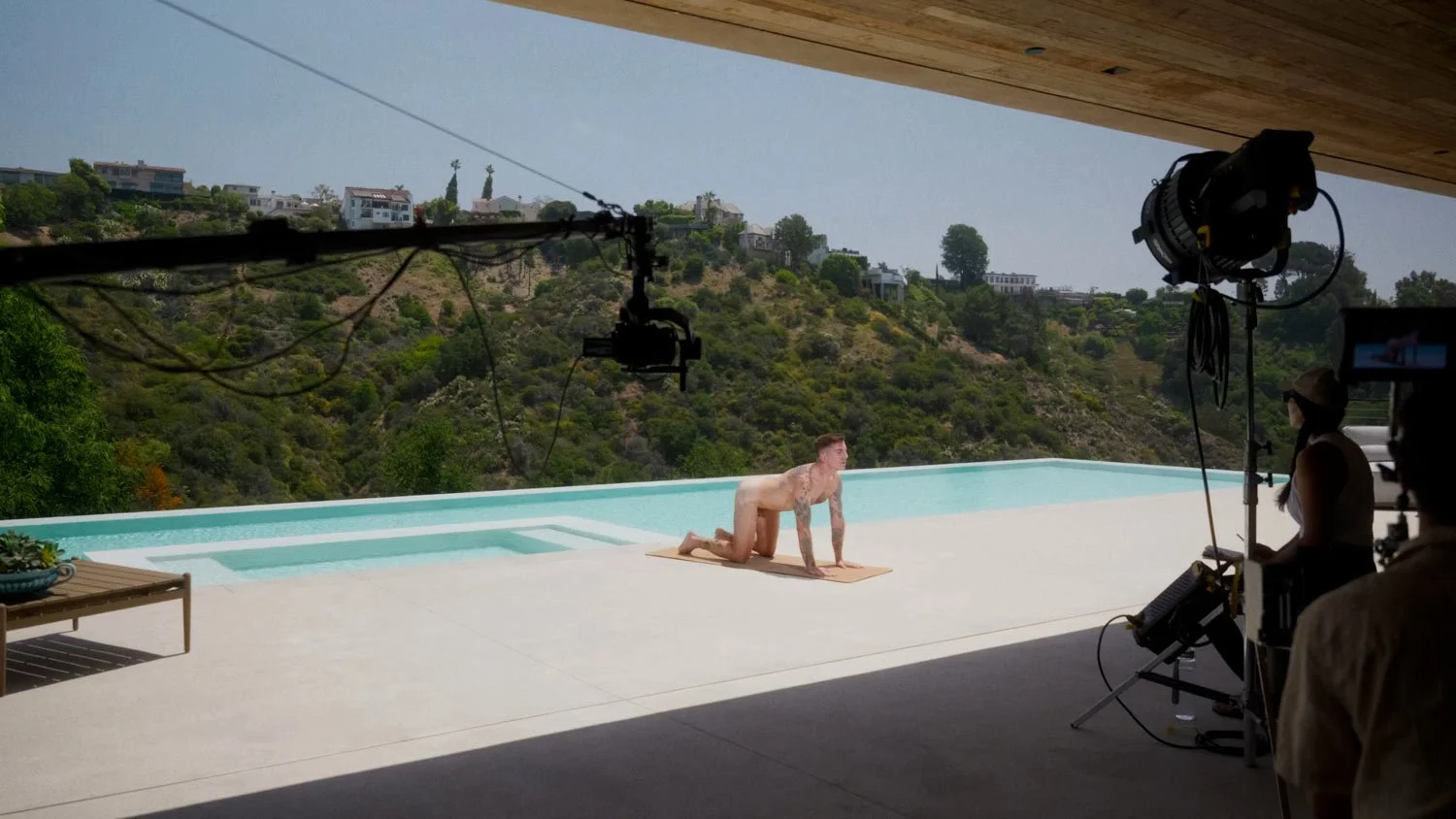 naked man on movie set doing nude yoga by a pool