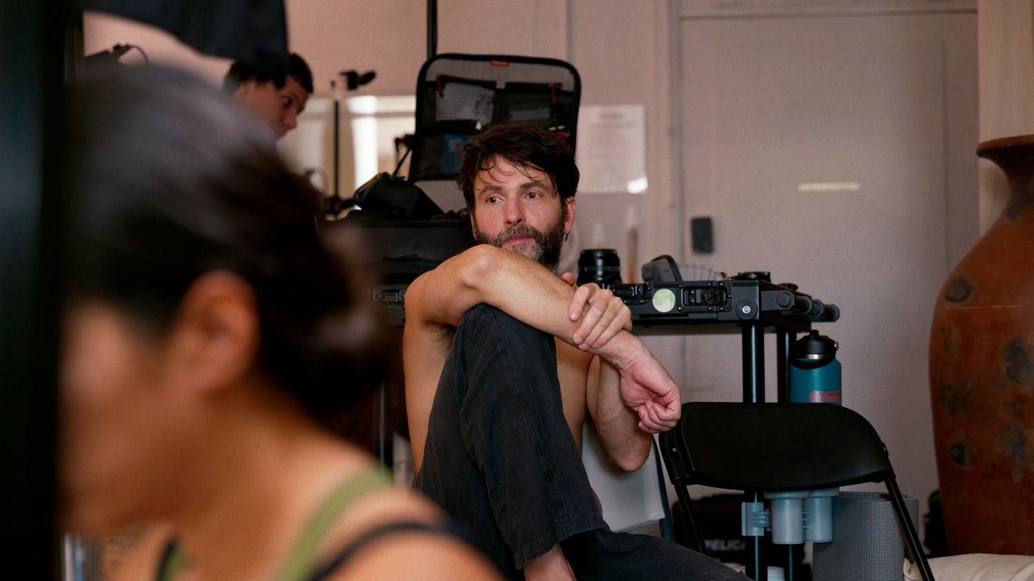 shirtless man sitting on the set of a video