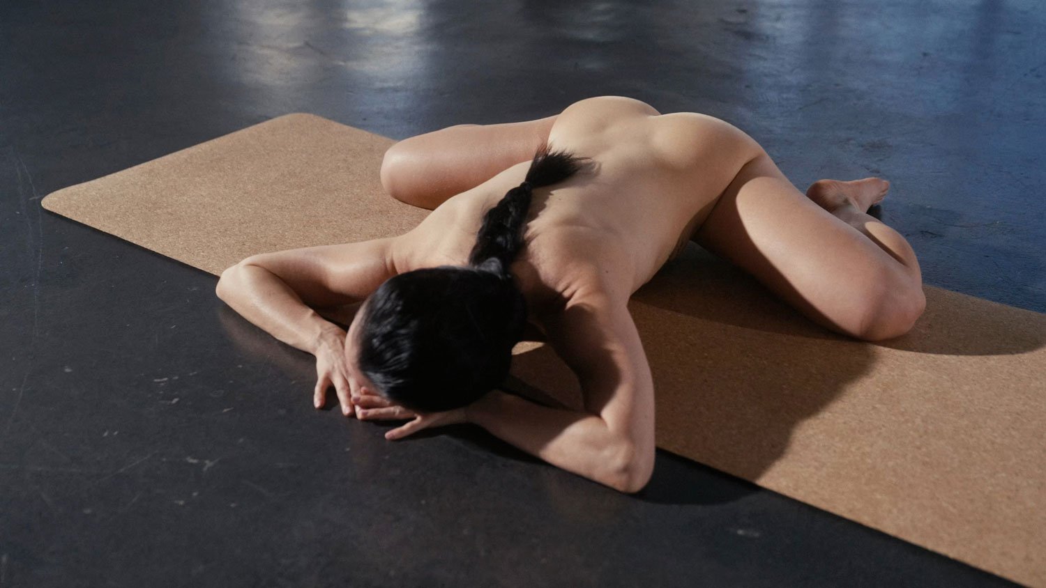nude woman in frog pose on cork yoga mat