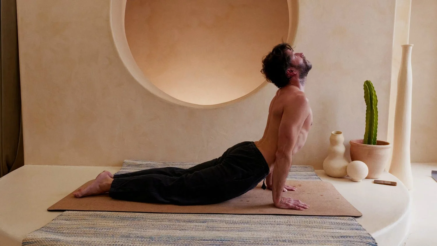 shirtless man in upward dog on a yoga mat