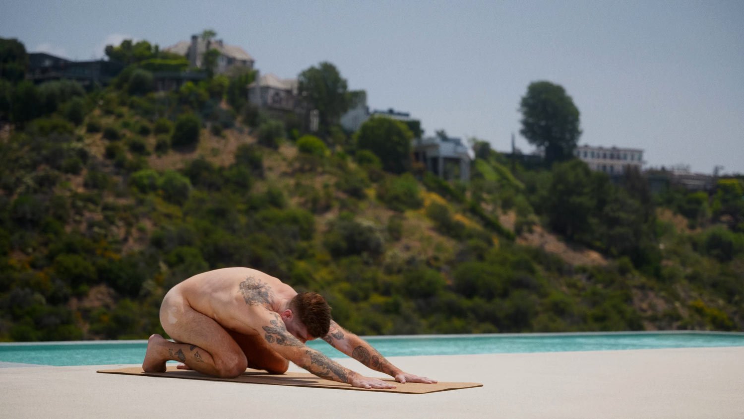 man practicing naked yoga in childs pose