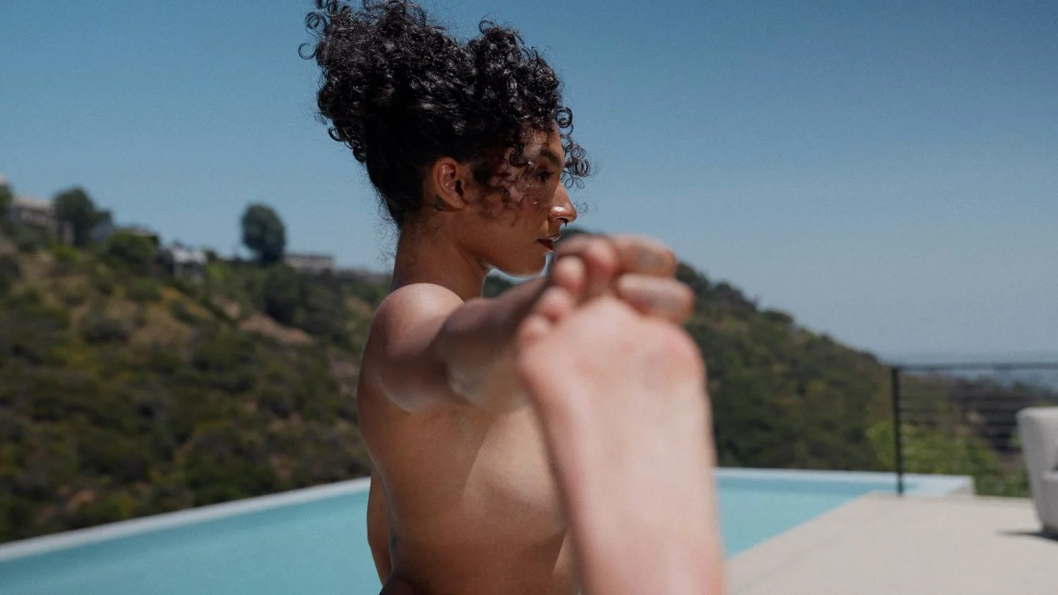 nude woman in hand to big toe pose outside