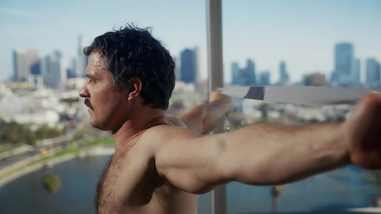 shirtless man holding a strap stretching his shoulders