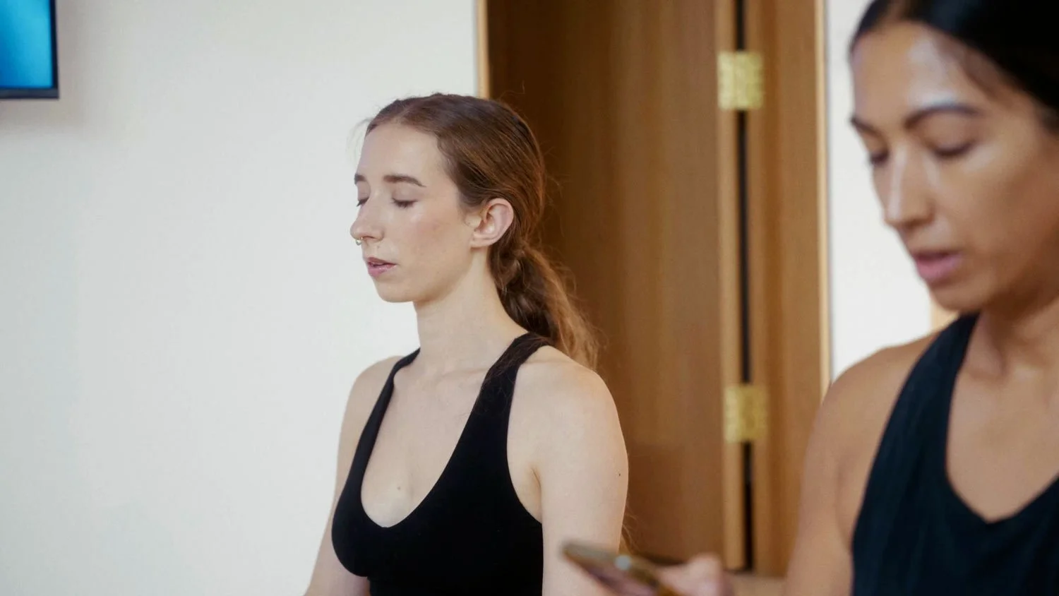 woman meditating with eyes closed in black halter top