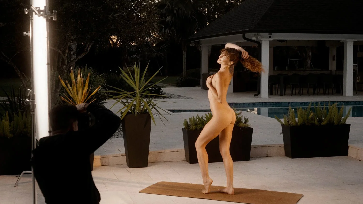 nude woman doing a photo shoot at twilight on a yoga mat