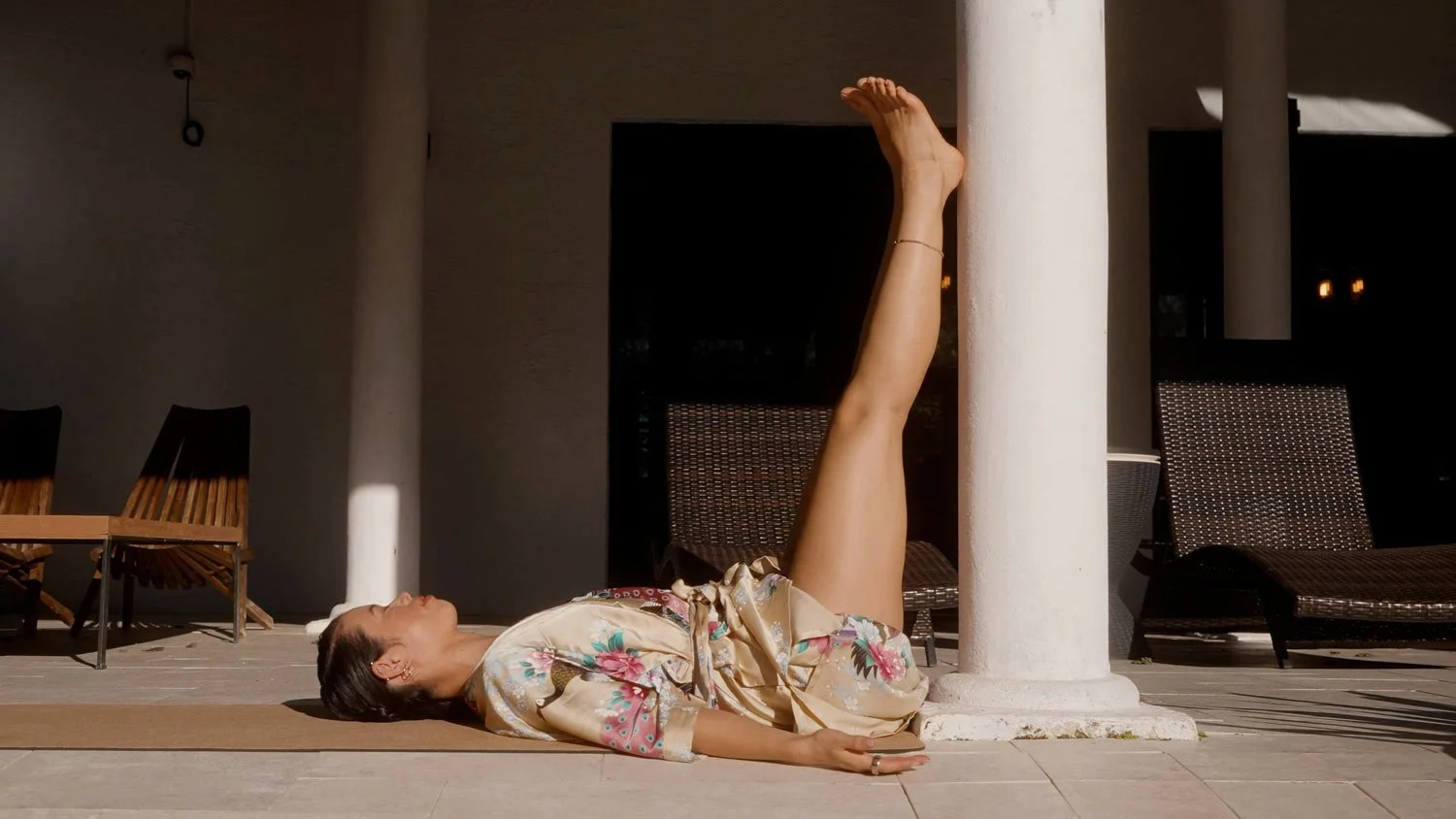 woman in waterfall pose with legs up on a column outside