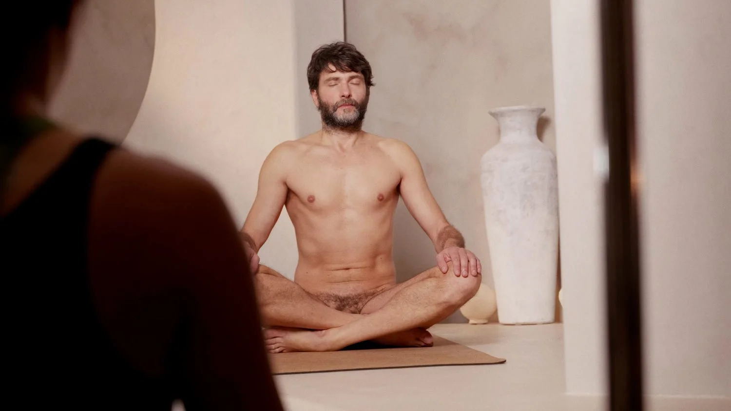 naked man in lotus pose on yoga mat