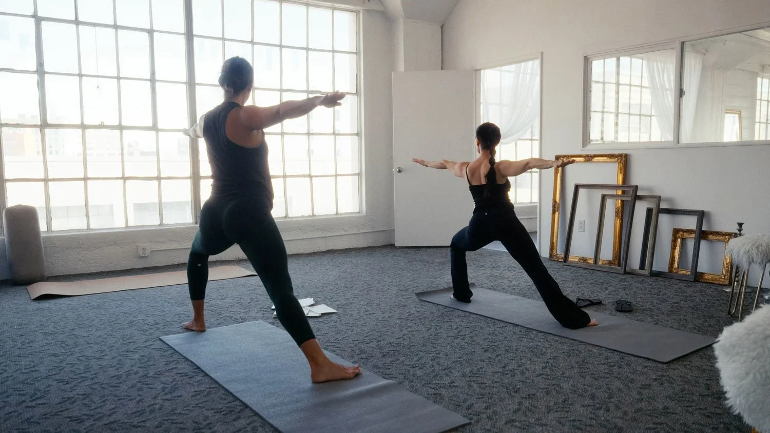 two woman practicing yoga in warrior two pose