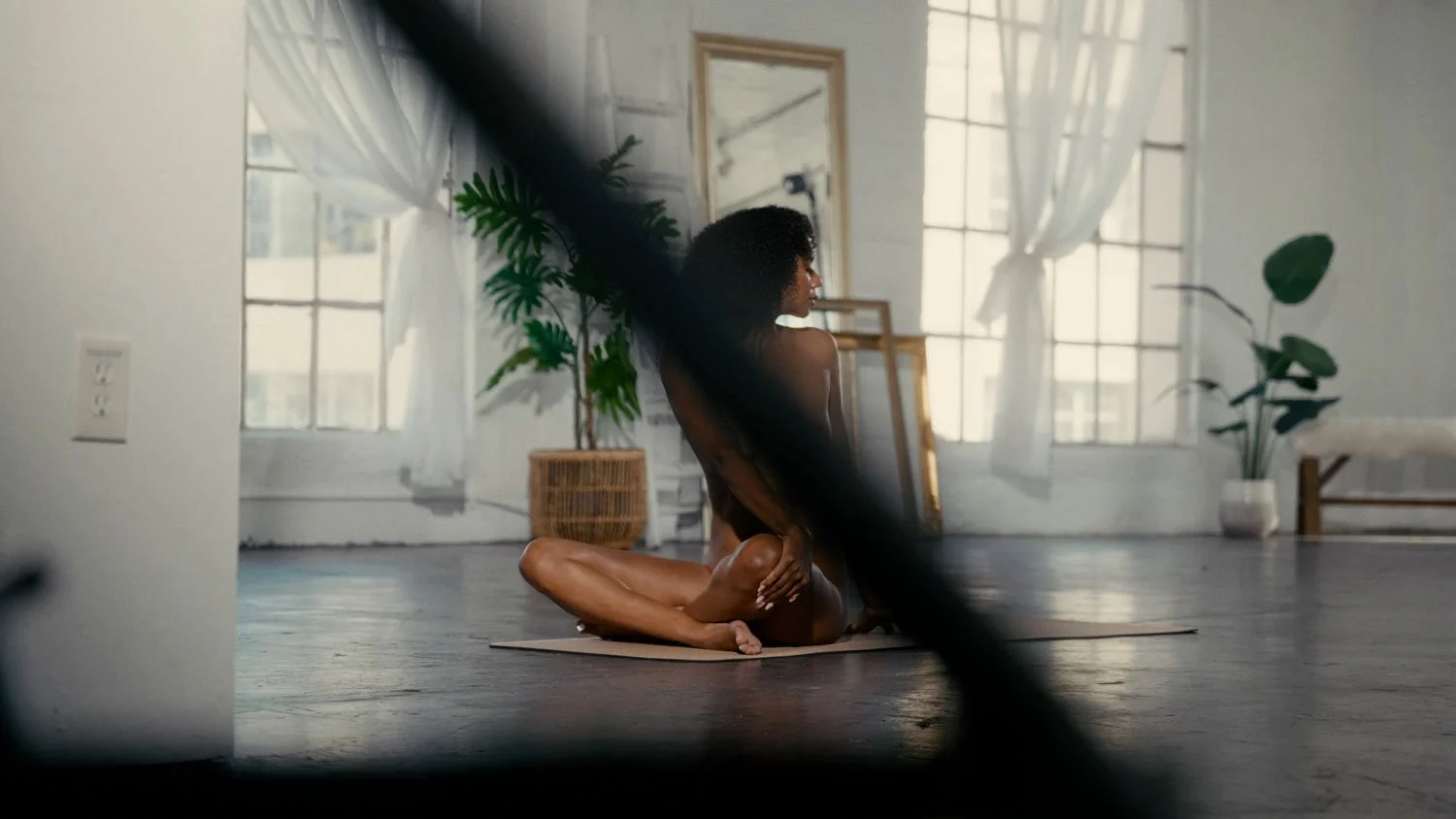 nude woman in seated twist practicing naked yoga