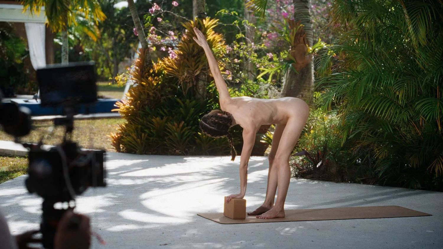 woman on the set of a nude yoga shoot in revolved triangle pose