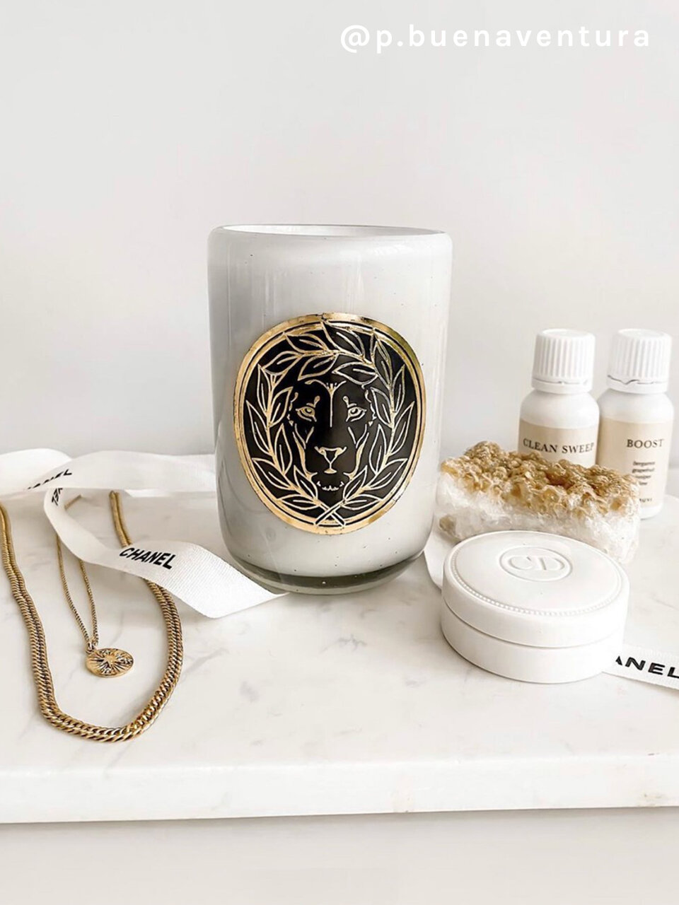 A white candle with a gold lion on a vanity