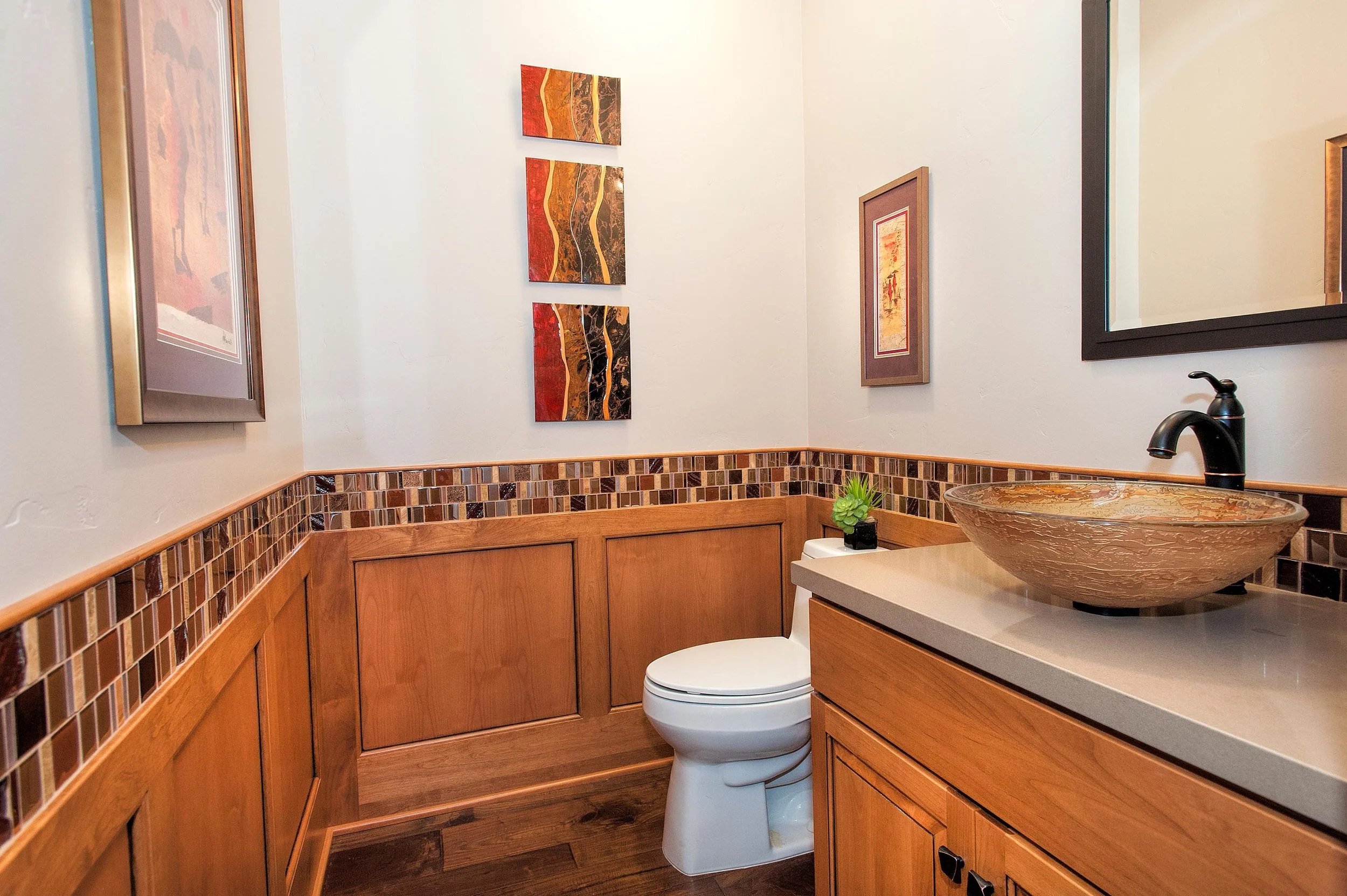 Elegant bathroom with wood look tile flooring, painting and cabinet