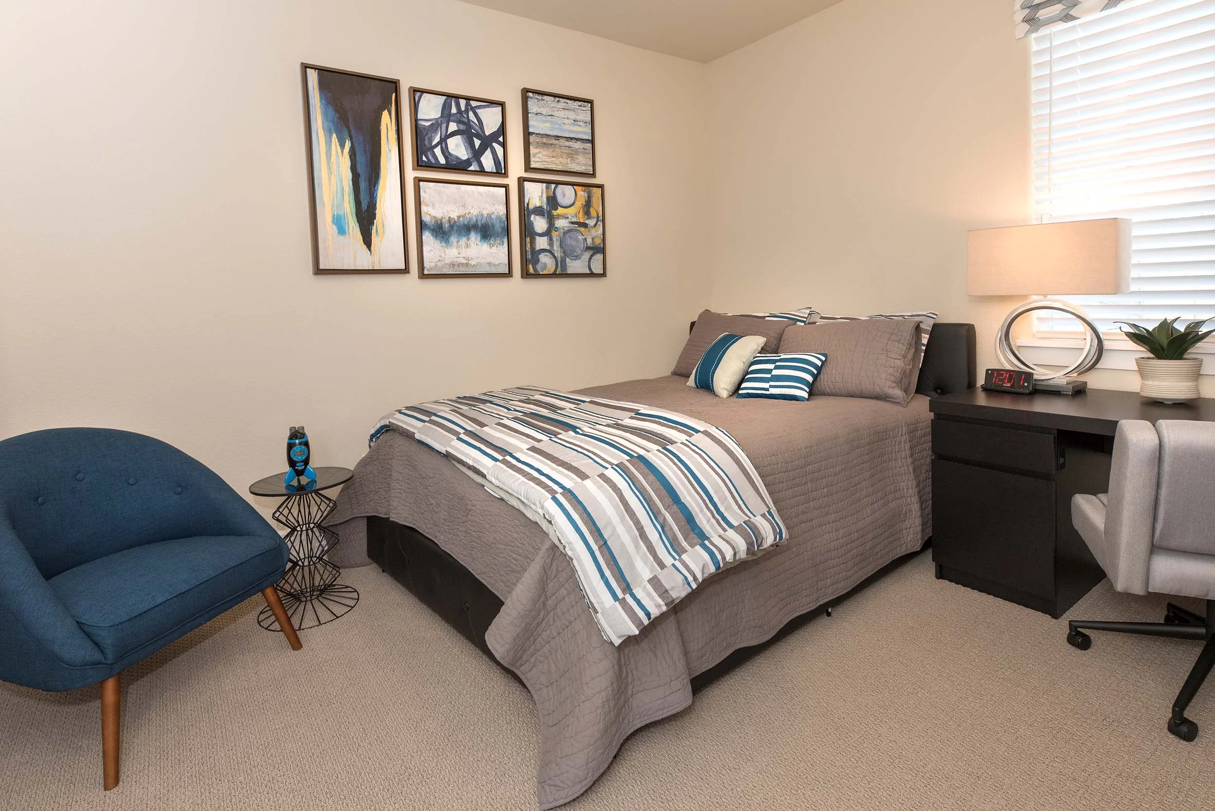Modern bedroom with bed, chair and frames on wall