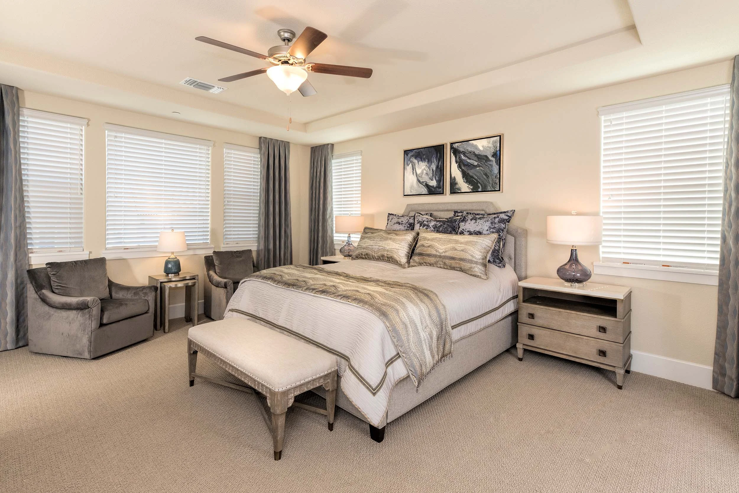 Modern bedroom with bed, bedside table, table lamps, ceiling fan and armchair