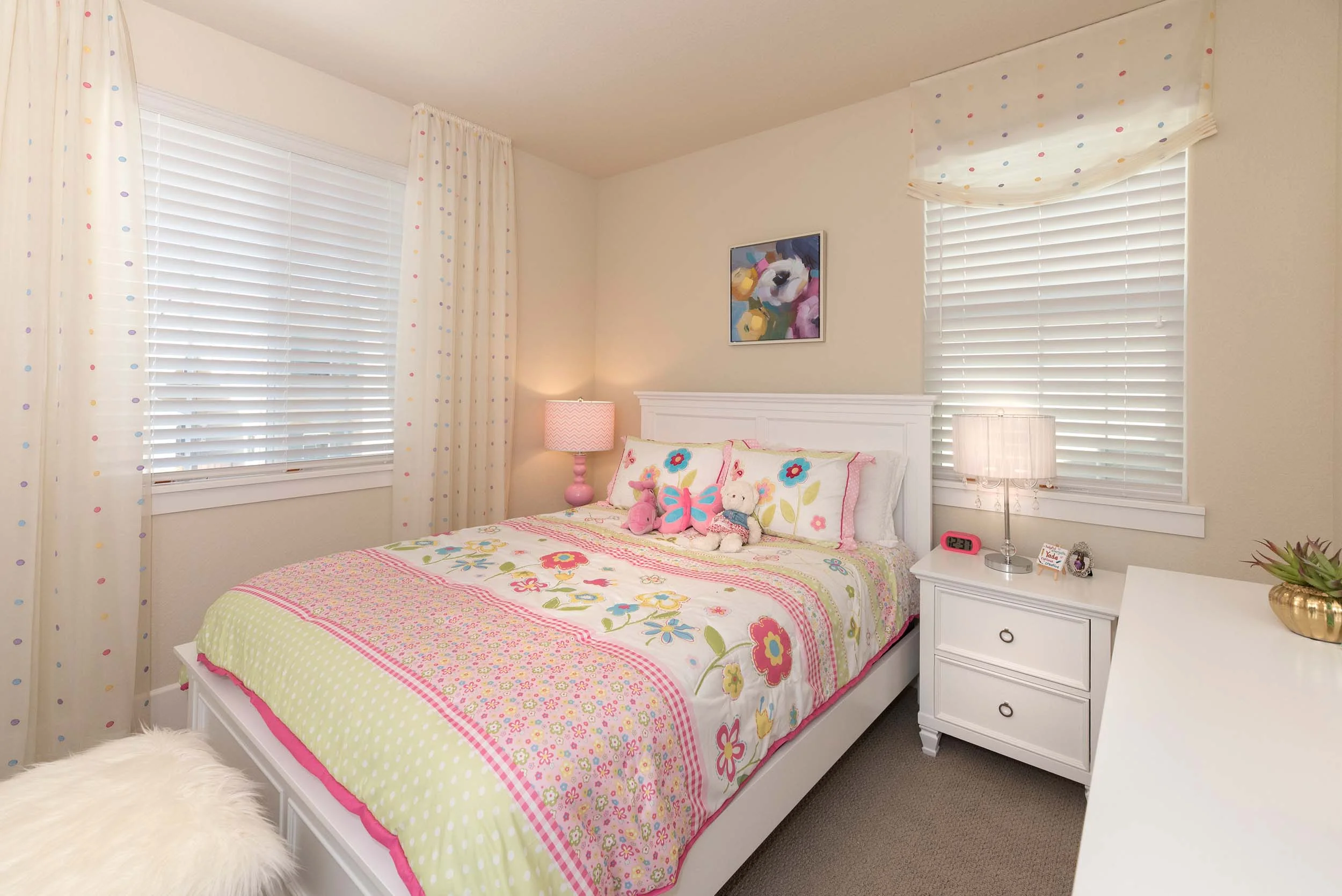 Small bedroom with pink bedsheet, bedside table and table lamps