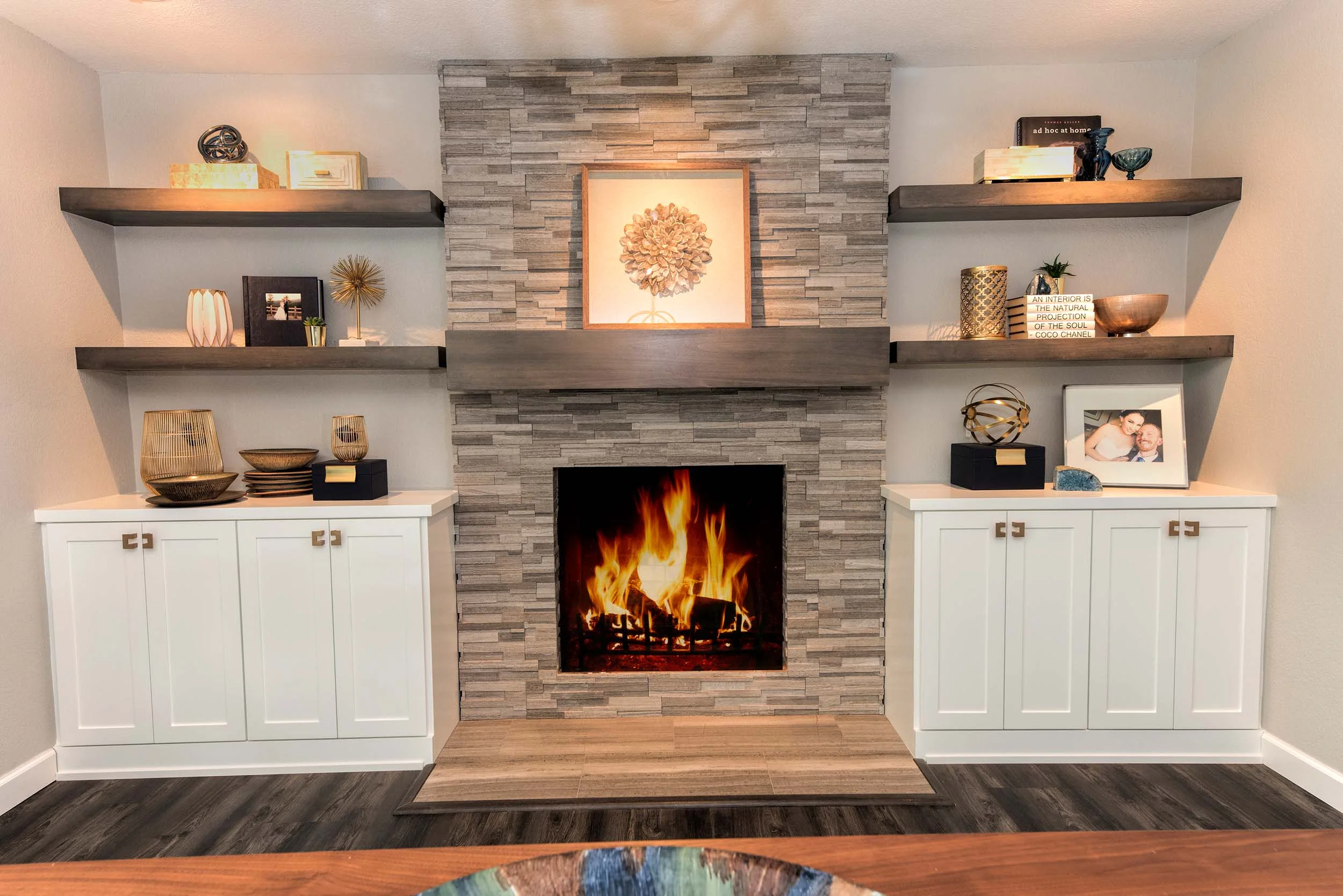 House interior with stone fireplace, hardwood floor, built-in shelves and cabinet