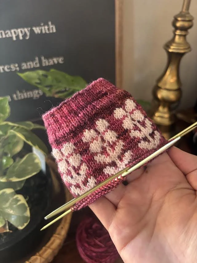 Holding unfinished sock project with floral colorwork detail