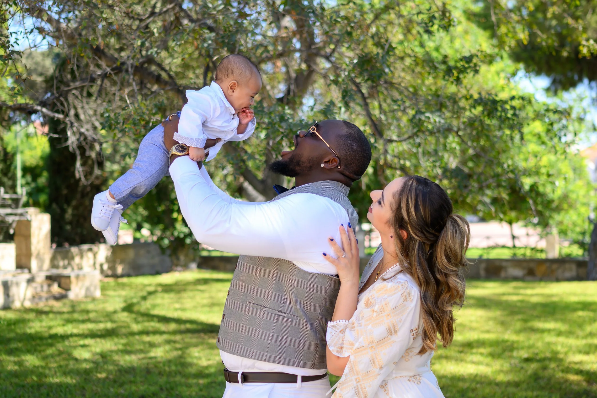 A man with a woman holding a young boy in the outdoor park.
