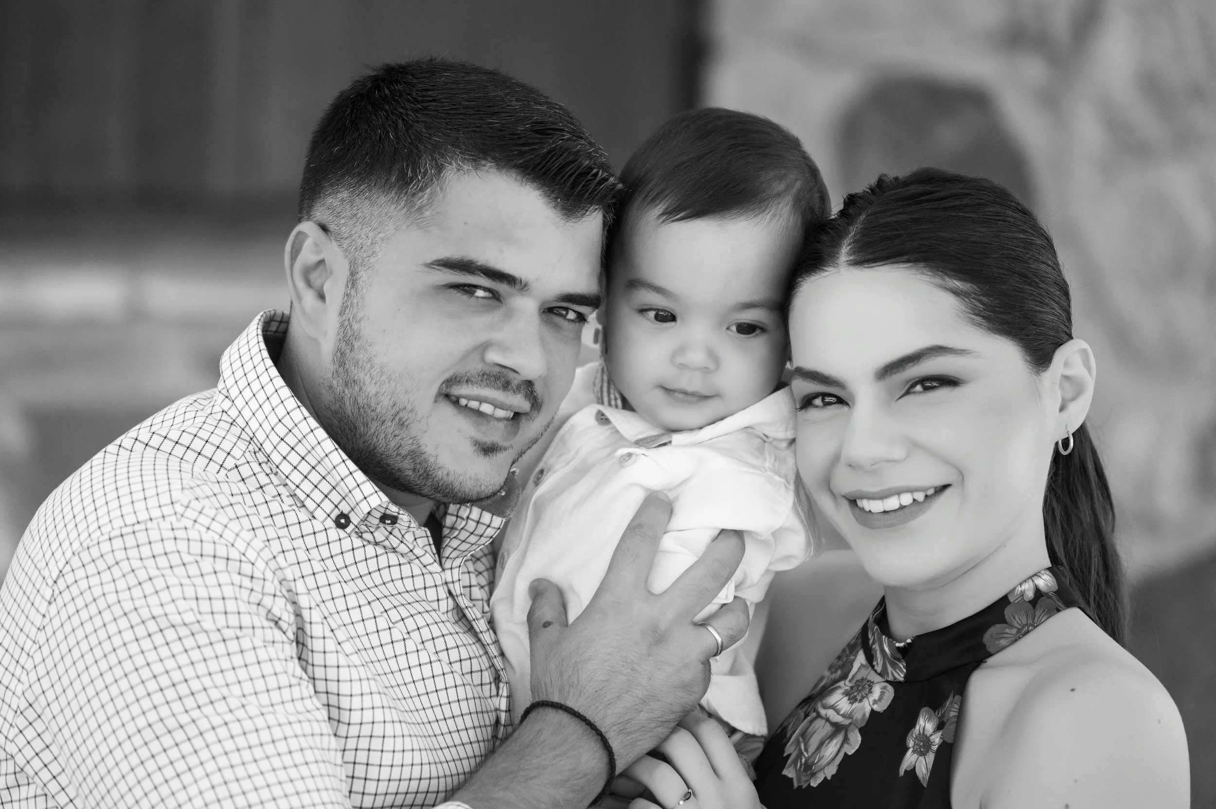 A black and white photo of a happy family with a man, woman, and a young child, all smiling and close together.