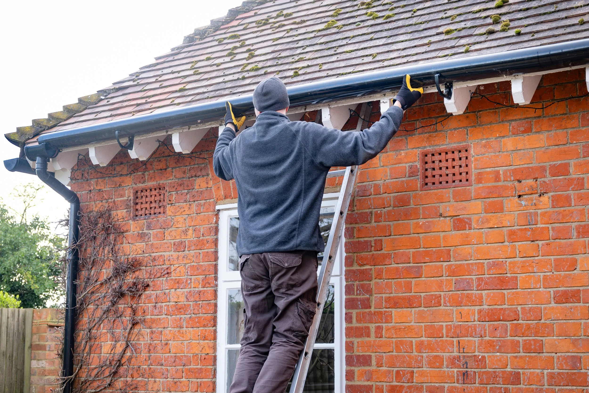 AdobeStock_919209314 man on ladder cleaning gutters.jpeg