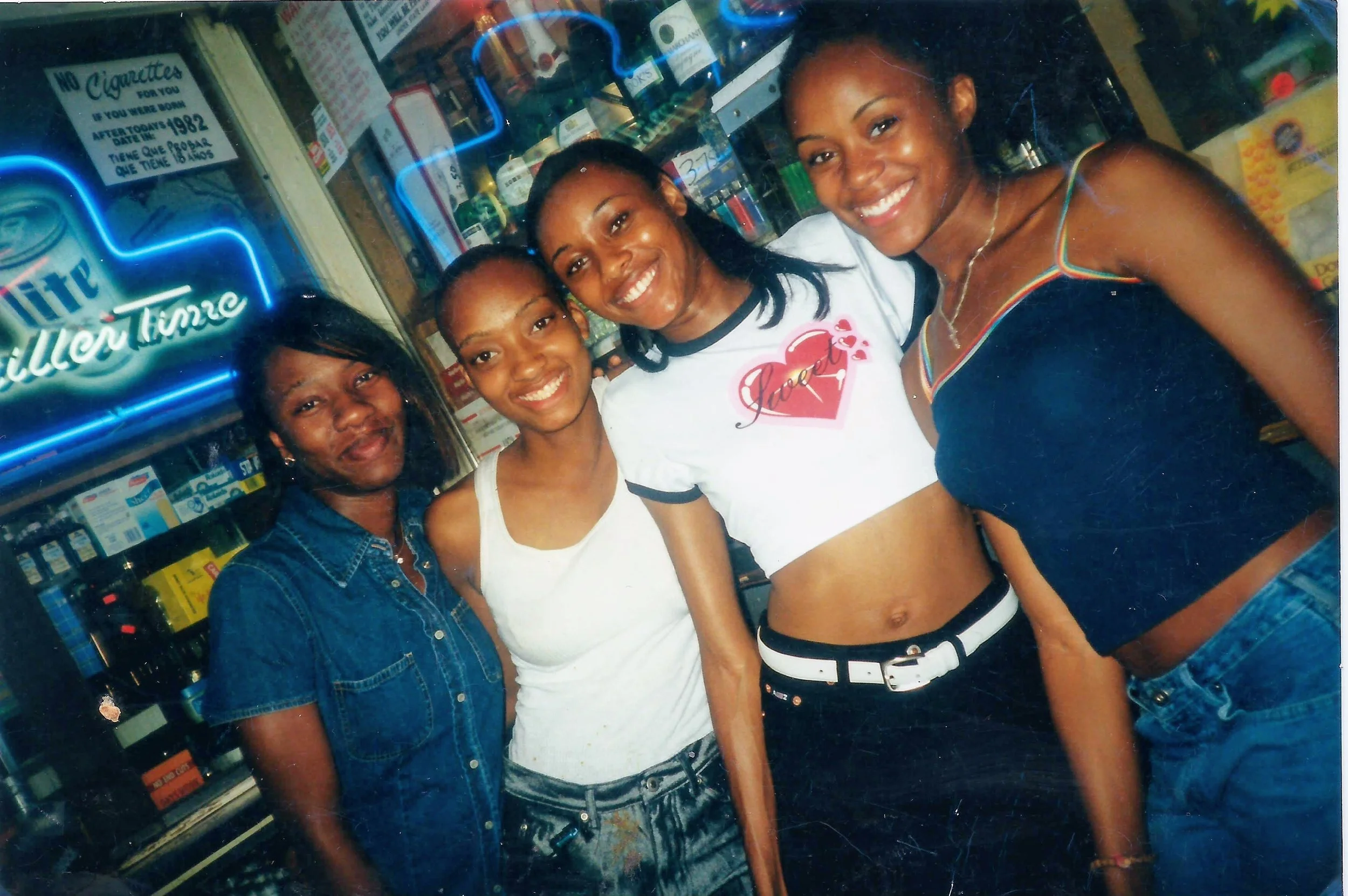 Midnight - September 2, 2000 This picture was taken in a liquor store in my 21st birthday. I’d talked my parents into letting me have a party starting on the 1st at around 930 or 10pm. At midnight, I would go to the store and buy my first bottle of alcohol as an official adult. The lady behind the counter asked for my ID, checked my birthday and said “Baby you have to be 21!” I proudly proclaimed “But it’s midnight, I am 21”. She got as excited as we were. She ran from behind the counter, gave me a birthday hug and offered to take this picture of us (because of course I had a camera with me). There to celebrate with me was my sister, my cousin RisCinda and our friend Devonya. I only took maybe one sip of the drink, I just wanted the experience 