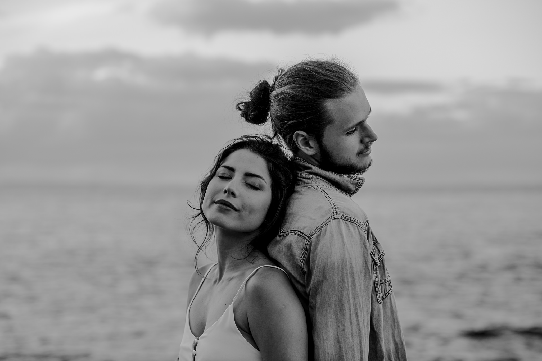 couple standing back to back breathing in the air causeway coastal engagement session