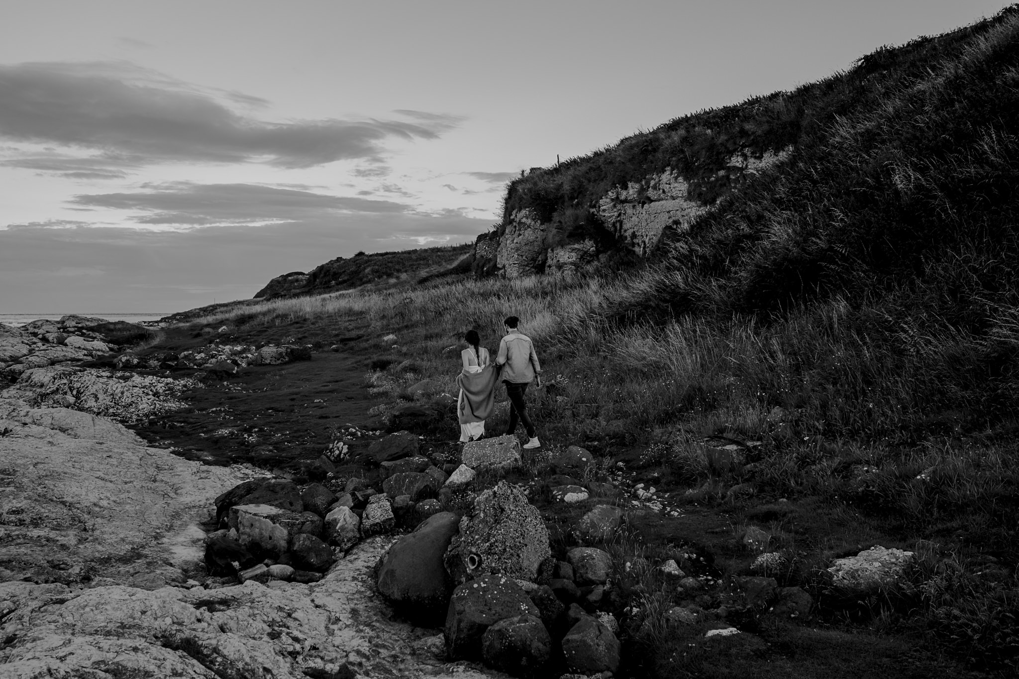  couple walking over rocks on the causeway coastal route engagement photographer 