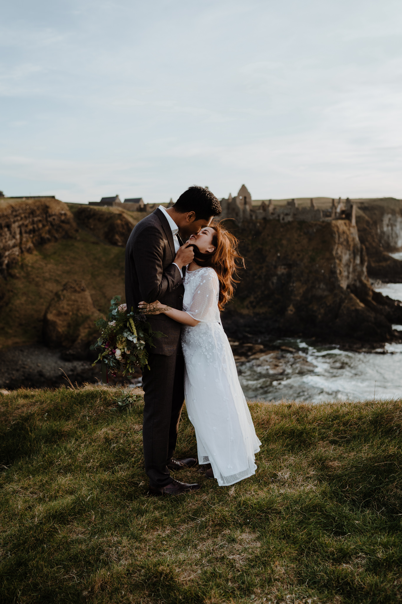 Engaged couple kiss sunset dunluce castle adventure elopement