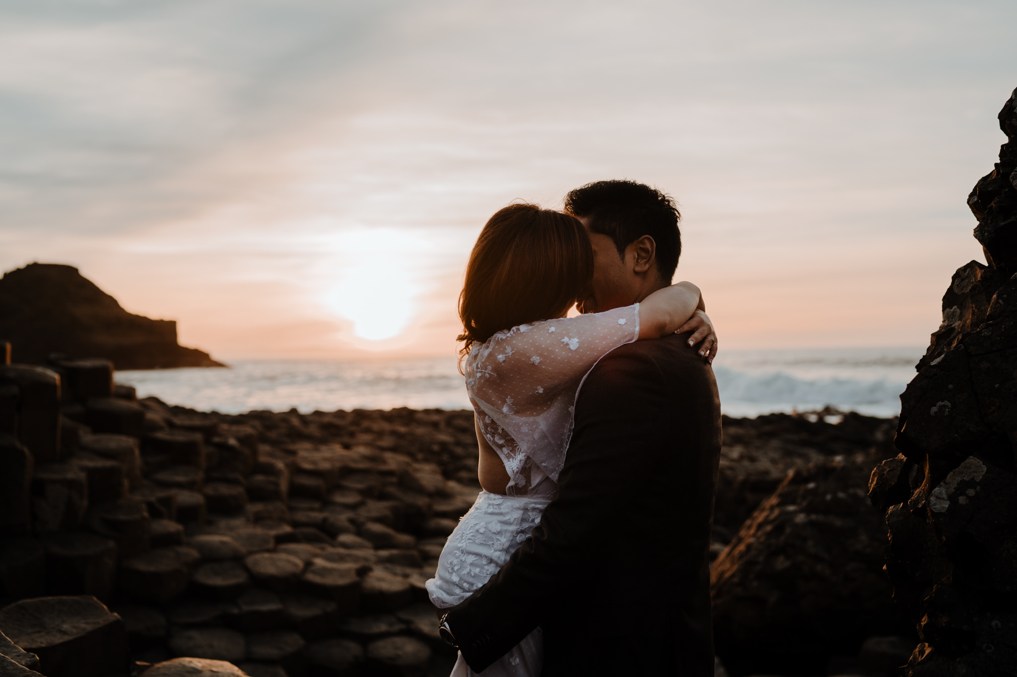 Asian couple embrace during sunset giants causeway adventure couples session