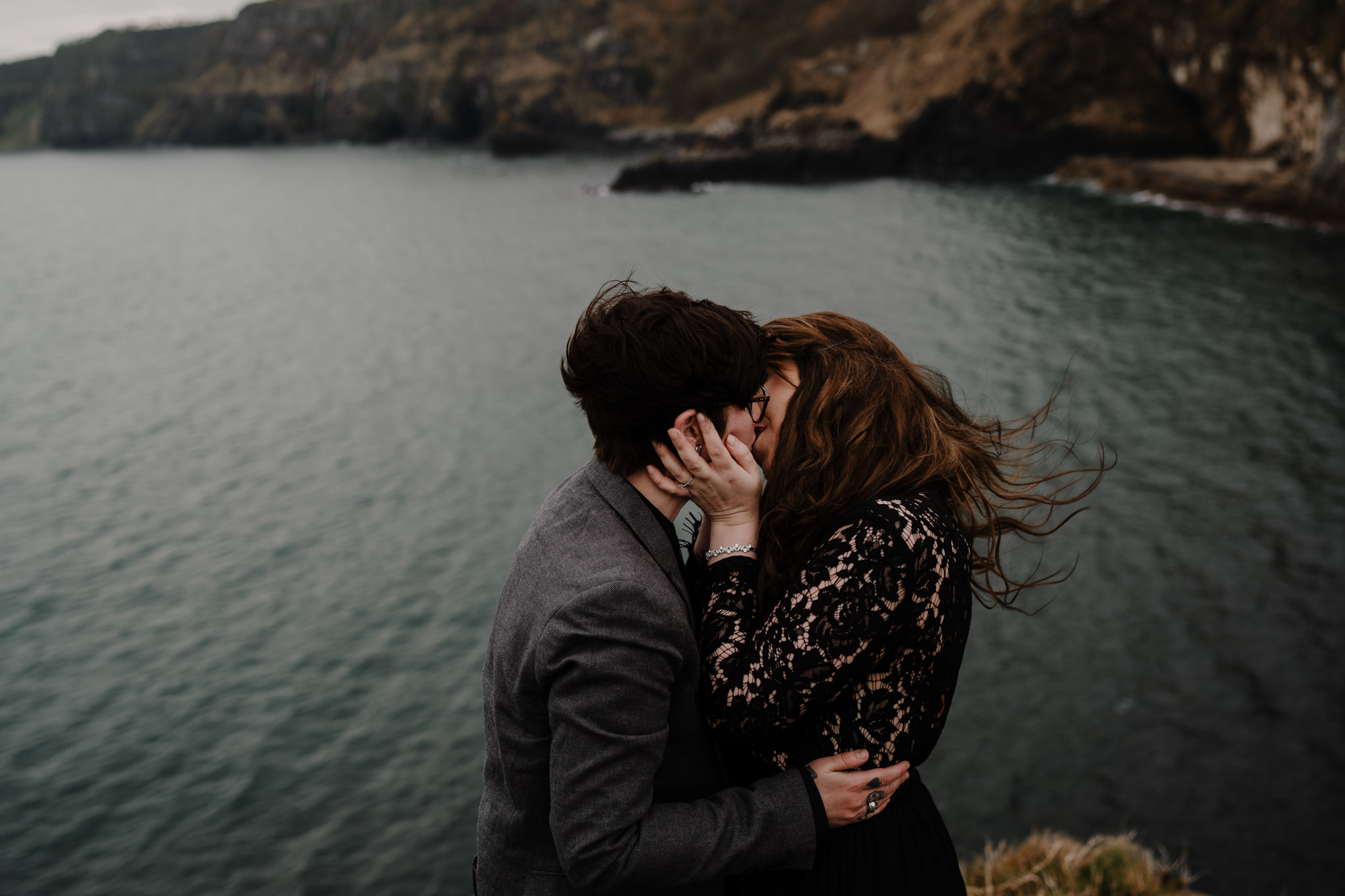 LGBTQ couple kiss windswept Kinbane castle adventure engagement photos