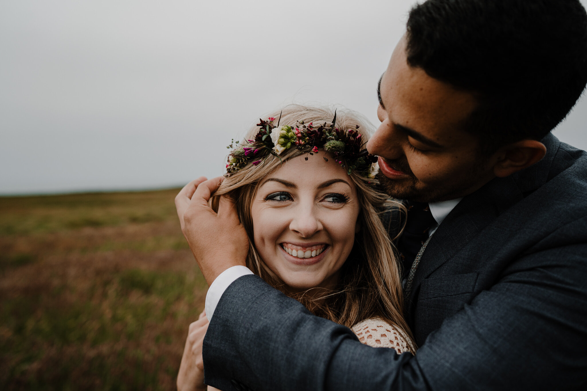 husband strokes hair of wifes face smiling flower crown ireland cliffs of moher anniversary session