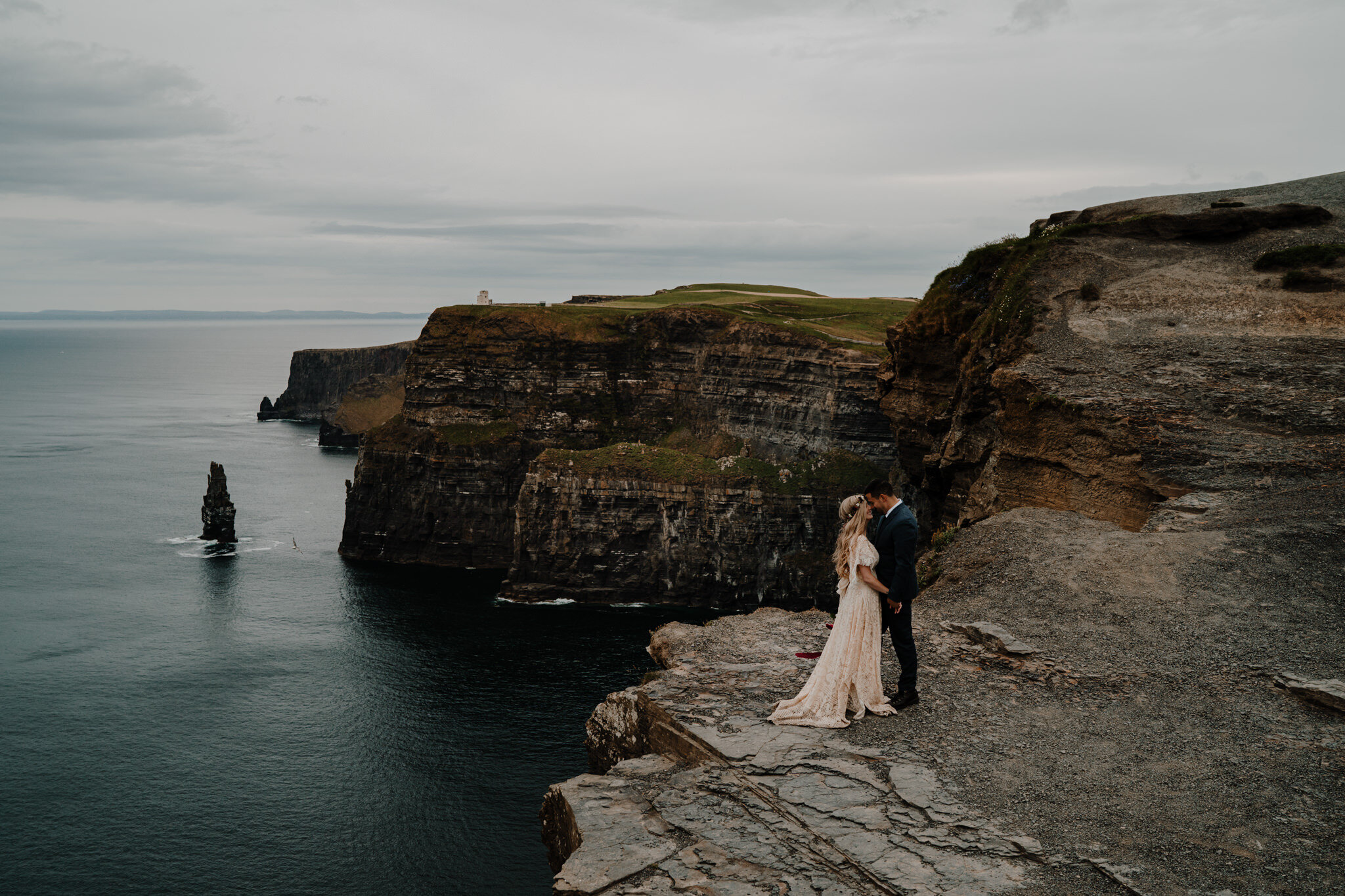 boho couple stand on cliff edge at cliffs of Moher session
