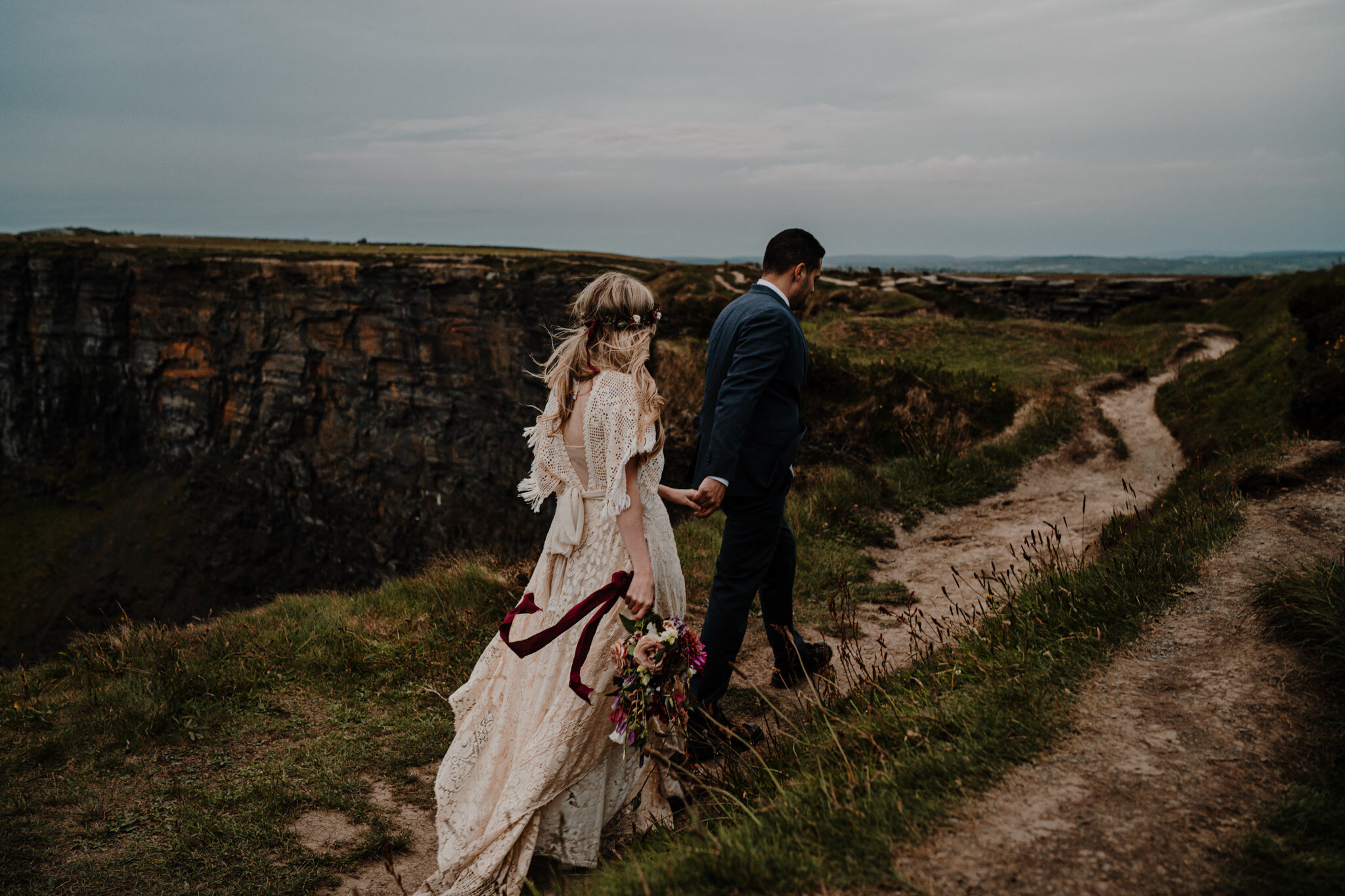 couple walk along cliff edge adventure elopement cliffs of moher ireland