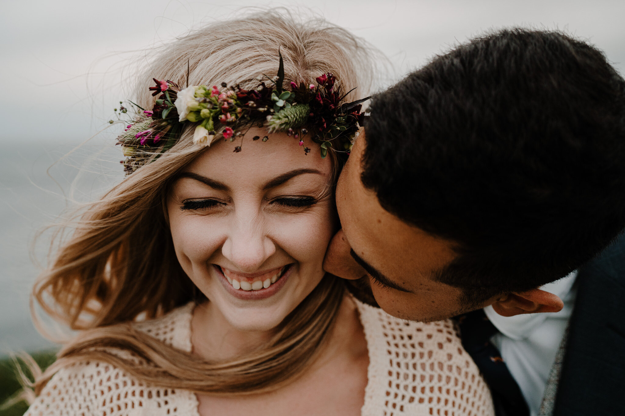 cute boho couple laughing close up kiss on cheek Cliffs of Moher ireland