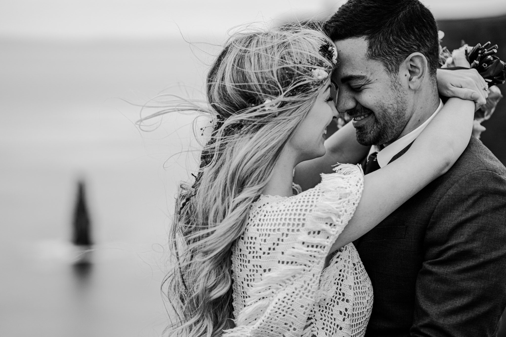 bw boho couple hug and smile at cliffs of moher anniversary session