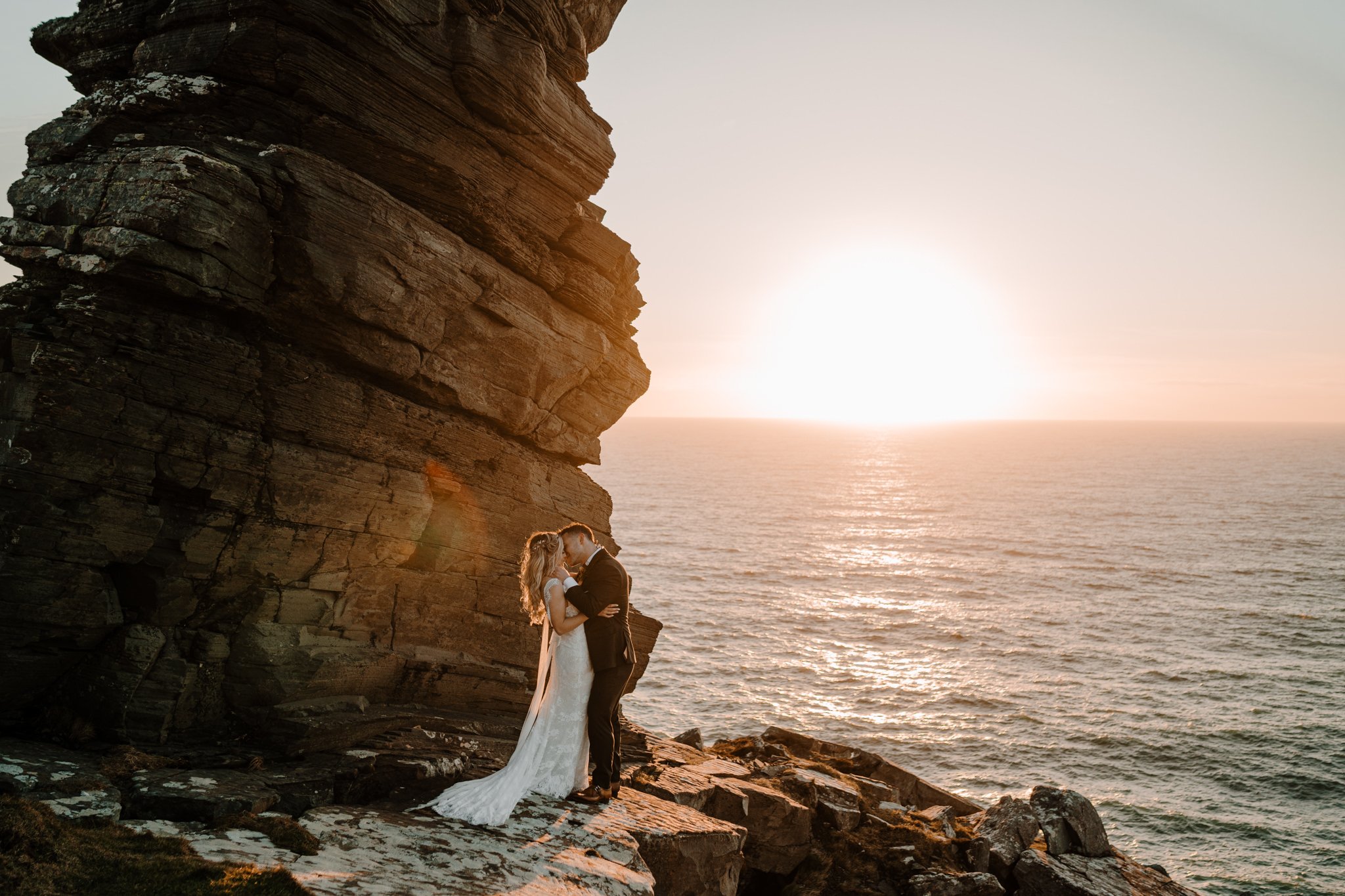  couple embrace during epic sunset during their Ireland elopement 