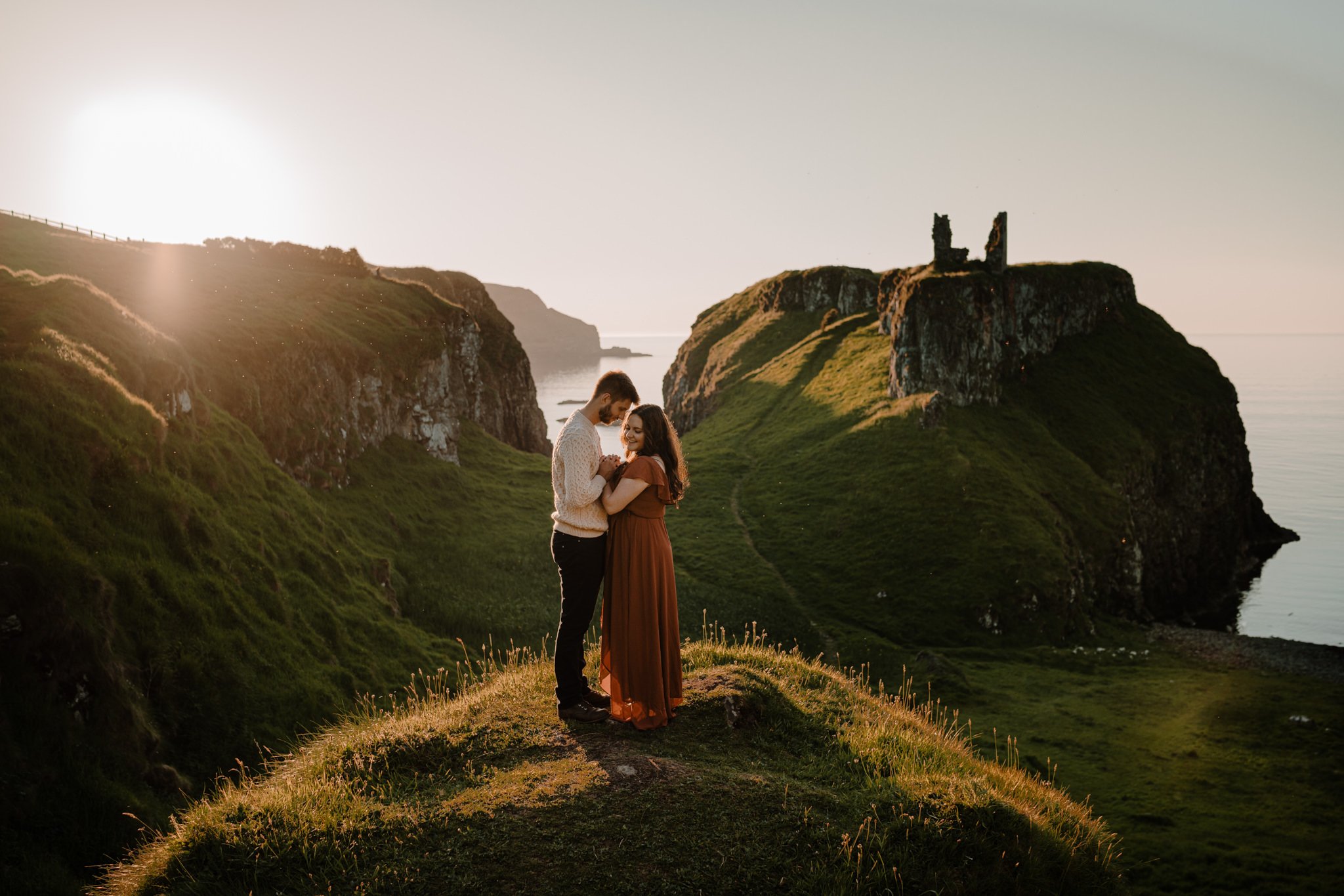 couple embrace in the sunset at dunseverick castle