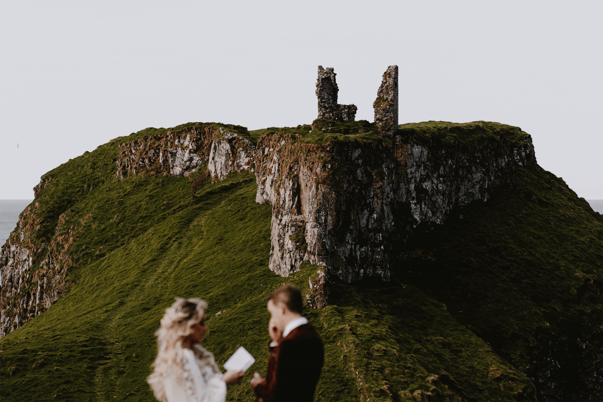 couple exchange vows infront of dunseverick castle during their elopement