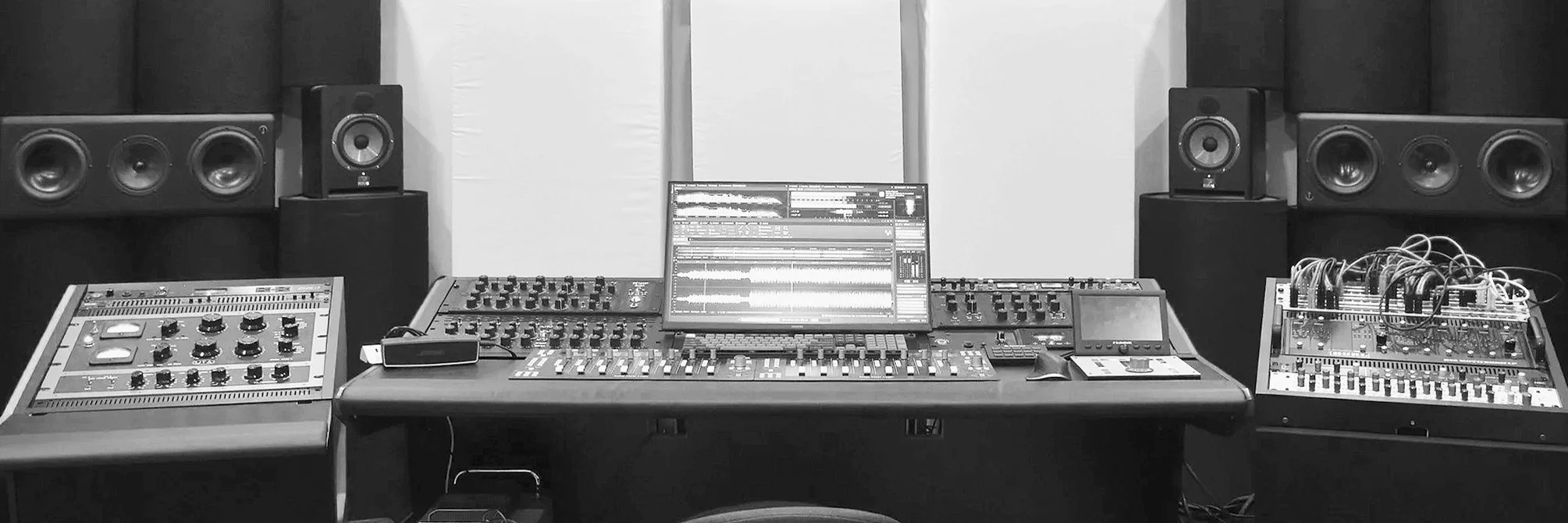 A high-end analog mastering studio with Ex Machina and Focal monitors. Wavelab is visible on a computer monitor surrounded by equalizers and compressors.