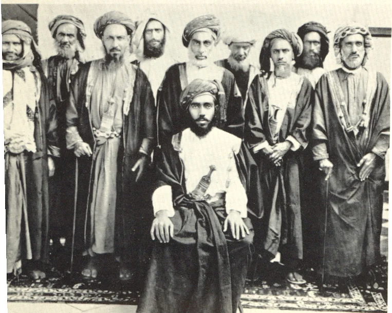السلطان_تيمور_بن_فيصل_و_خلفه_بعض_شيوخ_عمان.jpg