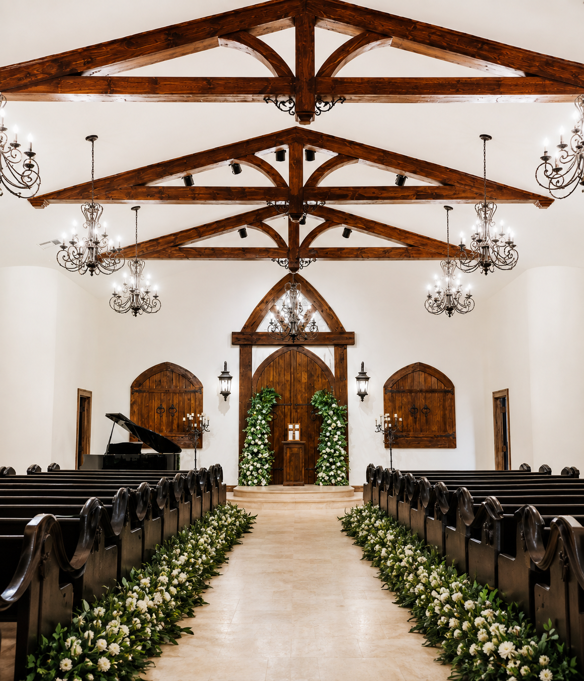 Interior of a wedding chapel with wooden beams, chandeliers, and floral decorations at the altar.